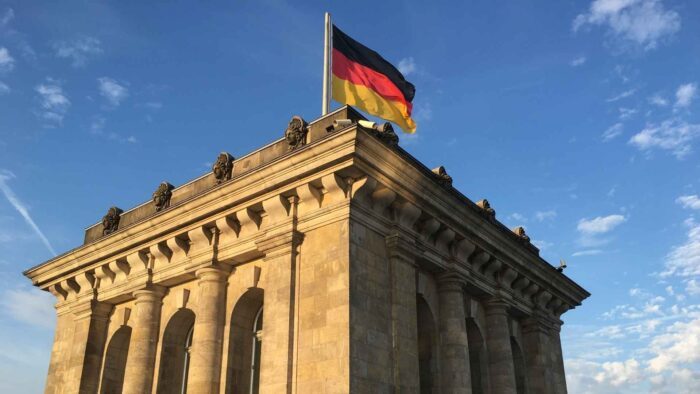 Deutsche Flagge weht auf dem Reichstagsgebäude in Berlin vor blauem Himmel.