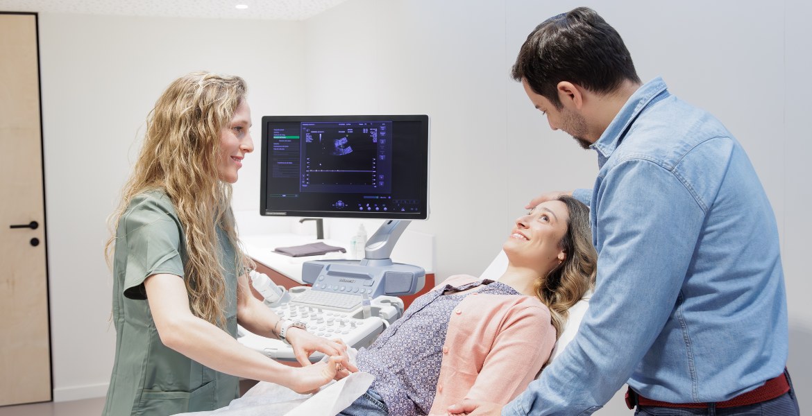 Ein Paar begleitet eine Patientin während einer medizinischen Ultraschalluntersuchung durch Fachpersonal in der Barcelona IVF Klinik.